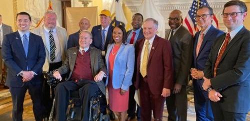 一大群州领导人，包括RIC主席华纳，州长. 麦基与前国会议员詹姆斯·朗格万在国际扶轮州议会大厦的州长厅聚会.