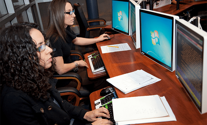 两个女学生并排坐在计算机实验室里 